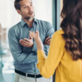 Standing man in business casual talking to standing woman in a yellow top